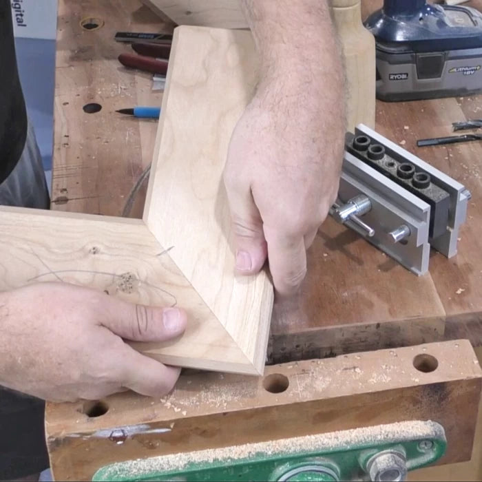 Woodworker holding mitered corners of wood pieces on workbench for precise joinery