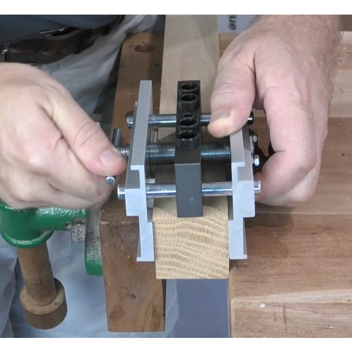 Woodworker using dowel jig on wood clamped to workbench for precise drilling