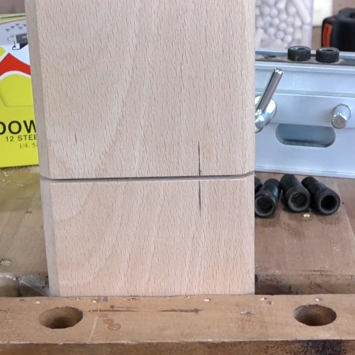 Marked wood pieces clamped for joinery on a woodworking table with dowel jig and hardware