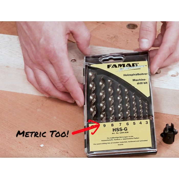 Hands holding FAMAG HSS-G metric drill bit set on a woodworking table