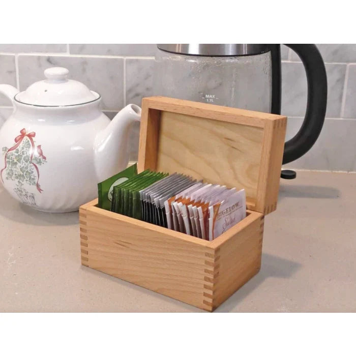 Wooden tea box with dovetail joints holding assorted tea bags on a kitchen counter
