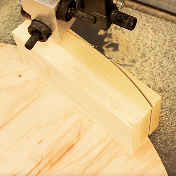 Band saw cutting curved shape in a wood block on a workshop table