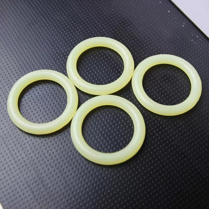 Four yellow router bit O-rings on textured black surface, woodworking tool accessory