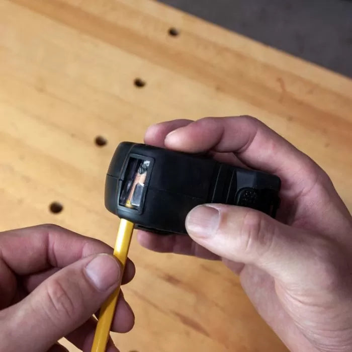 Hand-held pencil sharpener in use on a wooden workbench for woodworking marking tools