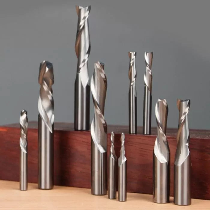 Assorted spiral router bits for woodworking displayed upright on a wooden surface