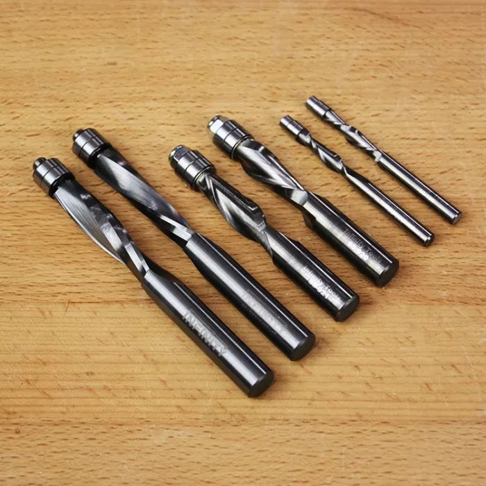 Set of six spiral flush trim router bits on wooden surface for woodworking projects