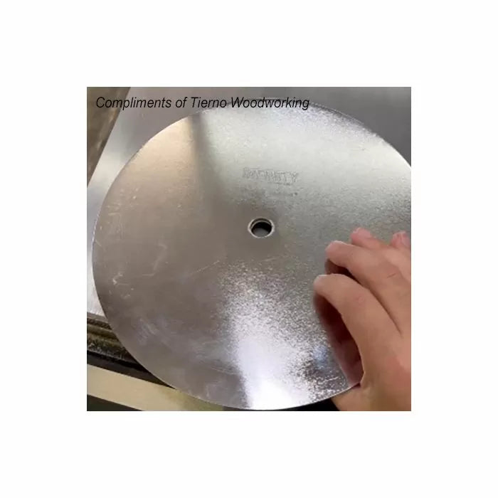 Hand holding a smooth table saw blade for woodworking on a metal surface