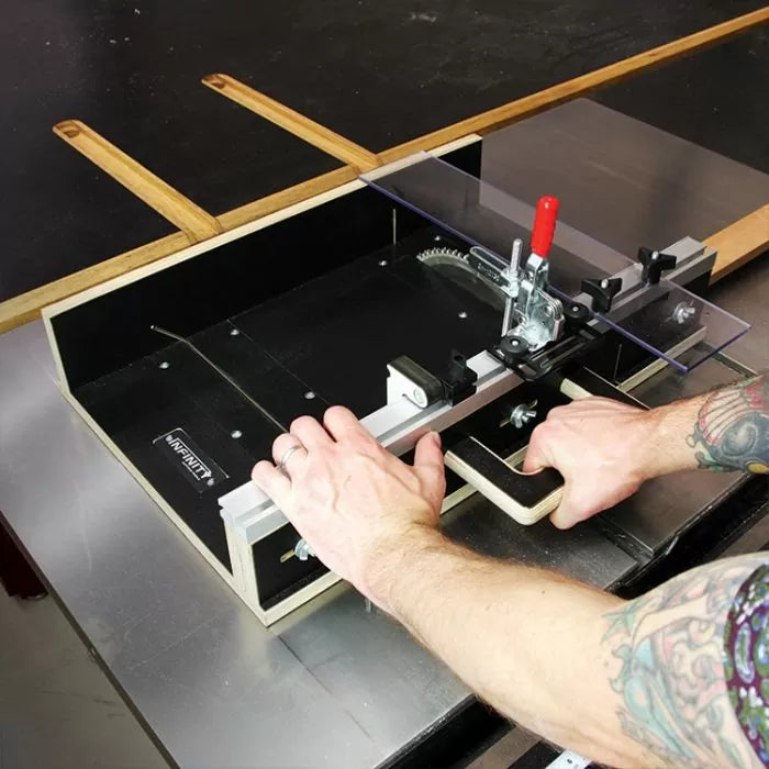 Table saw crosscut sled with clamp in use, cutting wood strips for woodworking precision.
