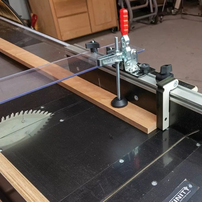 Table saw with safety fence, hold-down clamp, and clear blade guard set up for precise woodworking