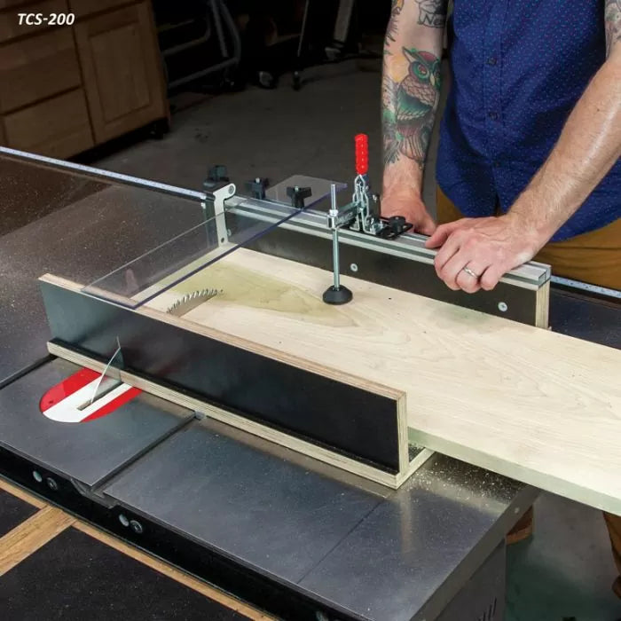 Woodworker using a table saw crosscut sled to cut a wooden board in a workshop