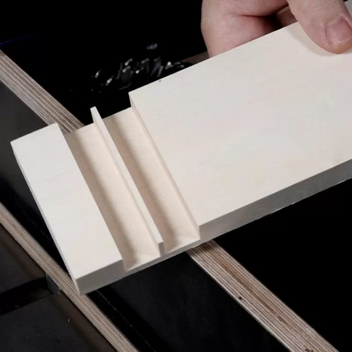 Hand holding a board with precise dado and groove cuts, woodworking joinery example