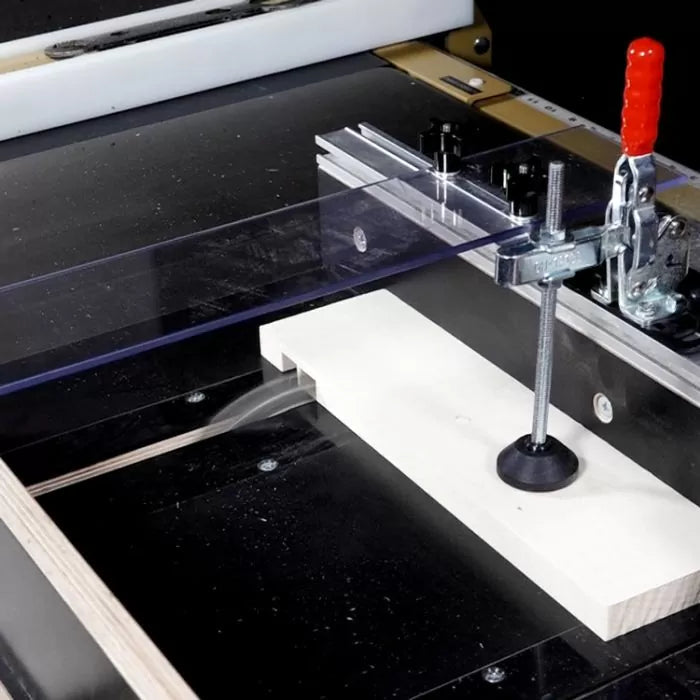 Router table setup with hold-down clamp and wood board for precise woodworking cuts