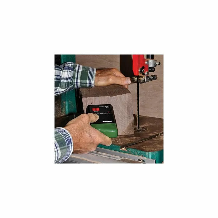 Woodworker using a digital pin moisture meter to test lumber before cutting on a bandsaw