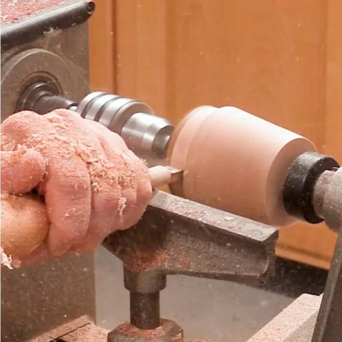 Woodturner using a lathe and turning tool to shape a wooden blank in a workshop