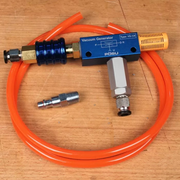 Vacuum generator kit with orange hose and metal fittings on a wooden workbench