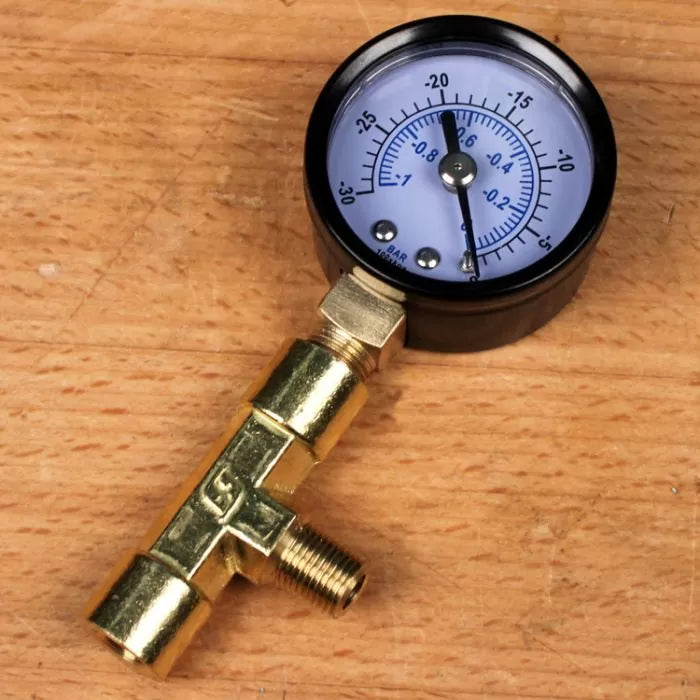Brass vacuum gauge with dial on a wooden surface, woodworking tool accessory