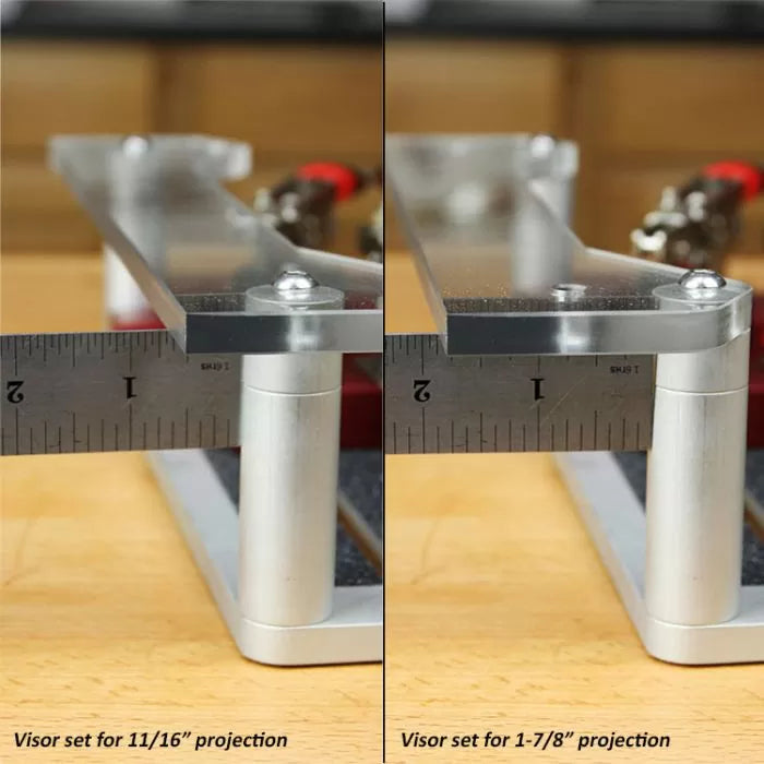 Close-up of adjustable router table visor extension showing two different projection settings with ruler measurements on a woodworking bench.