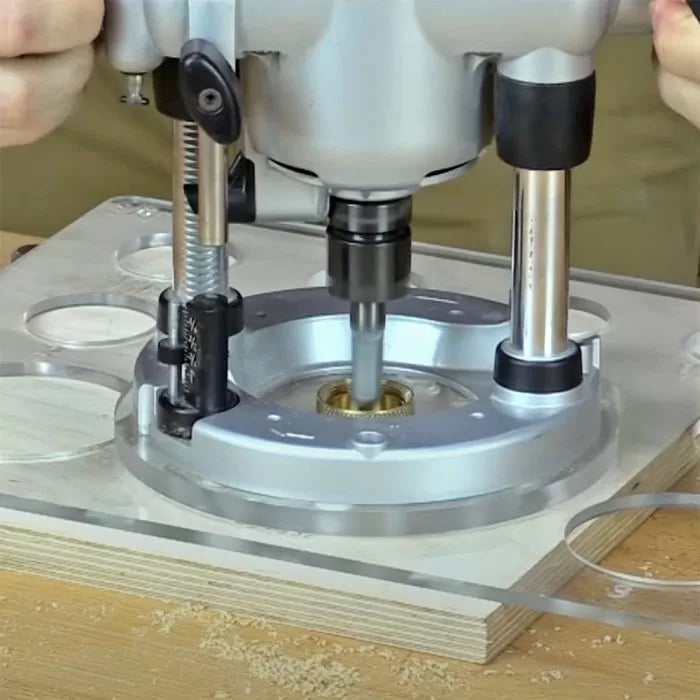 Plunge router on acrylic routing template and wood, woodworking tool in use