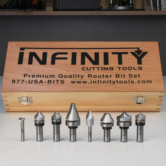 Woodworking router bit set with various profiles displayed in front of a wooden storage case.