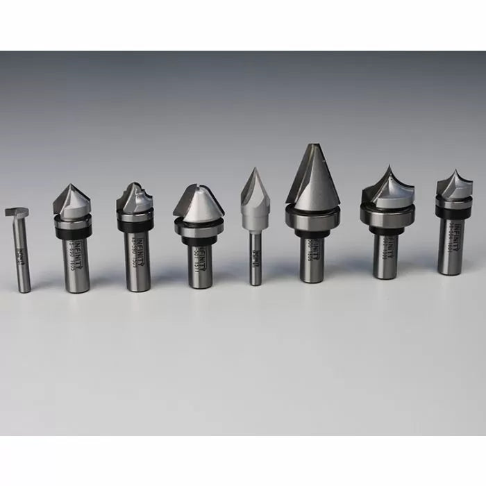Assorted woodworking router bits set on gray surface, precision cutting tools for wood.