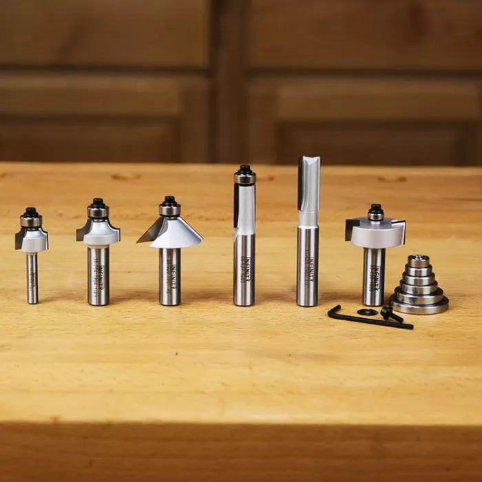 Woodworking router bit set with assorted profiles and accessories on a wooden table