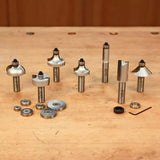 Assorted woodworking router bits and bearings set on a wooden workbench
