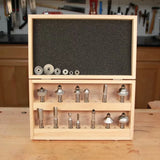Wood router bit set in wooden case with multiple bits and bearings on a workbench