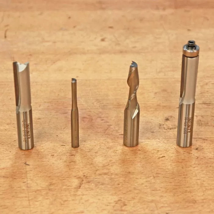 Four woodworking router bits in different sizes on a wooden workbench