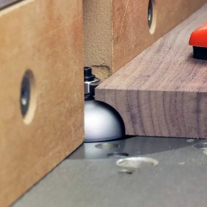 Wood router table with roundover bit cutting hardwood edge, woodworking tool closeup