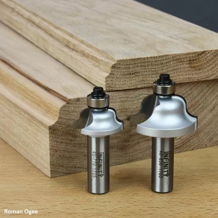 Roman ogee router bits with ball bearings beside shaped wood molding on workbench