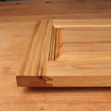 Closeup of unfinished wooden cabinet door with raised panel and decorative edge profile
