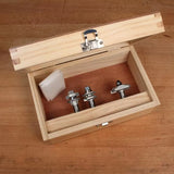 Wooden box containing three router bits for woodworking on a workbench