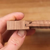 Hand holding two joined wood boards with a precise tongue and groove woodworking joint