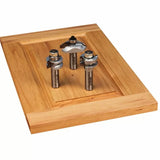 Three woodworking router bits on a wooden cabinet door panel