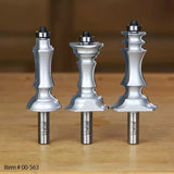 Three metal woodworking router bits with decorative profiles on a wooden surface