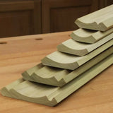 Stacked wooden crown molding trim pieces with detailed routed profiles on a workbench