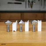 Set of three metal router bits with matching wood joinery samples on a workshop bench