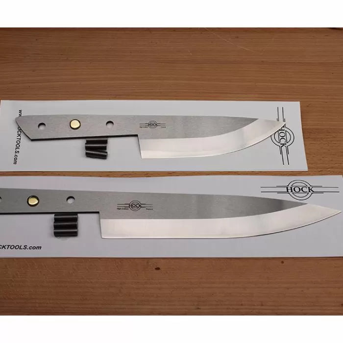 Two stainless steel knife blades with rivet holes, placed on a wooden surface.