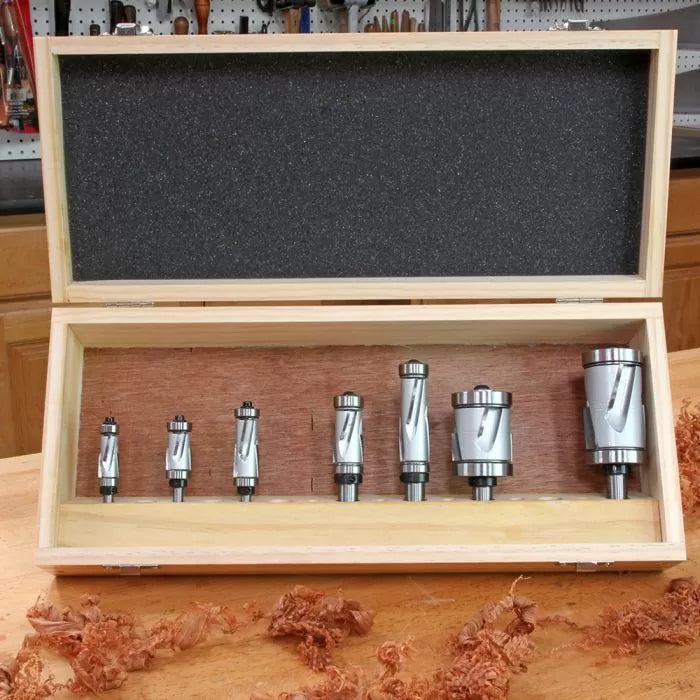 Set of seven carbide router bits in a wooden case on a woodworking bench