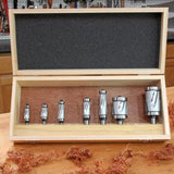 Set of seven carbide router bits in a wooden case on a woodworking bench