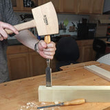Woodworker using a mallet and chisel to carve a mortise in a wooden board