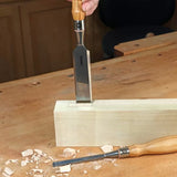 Wood chisel carving mortise joint in block of wood on woodworking bench