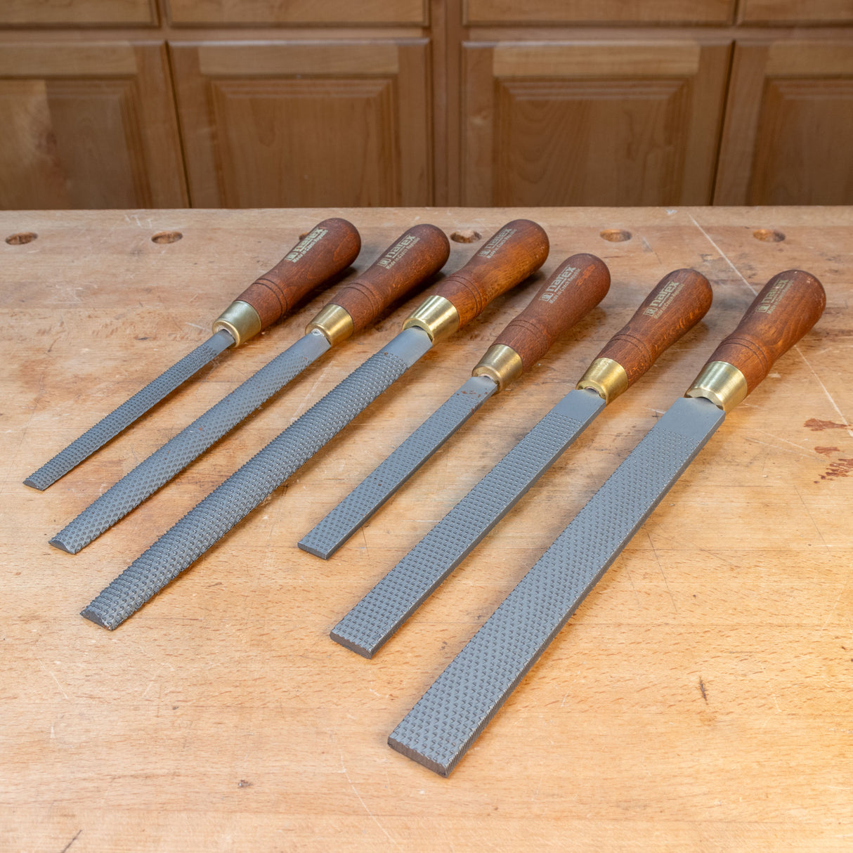 Six-piece premium woodworking rasp set with wooden handles on a workbench