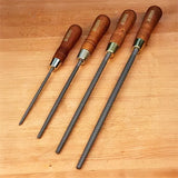 Set of four woodworking rasps with wooden handles on a wooden surface