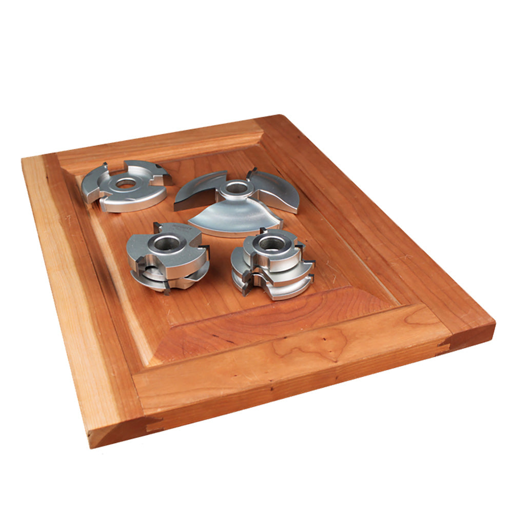 Cabinet door shaping cutters displayed on a finished wooden panel for woodworking