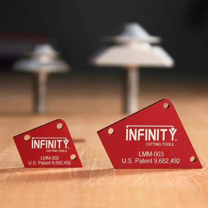 Two red Infinity Cutting Tools router bit setup guides on a wooden surface with blurred router bits in background