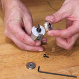 Hands assembling woodworking router bit with bearings and hex key on wooden workbench