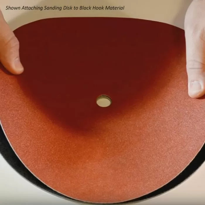 Attaching red sanding disk to black hook material for woodworking and sanding tools