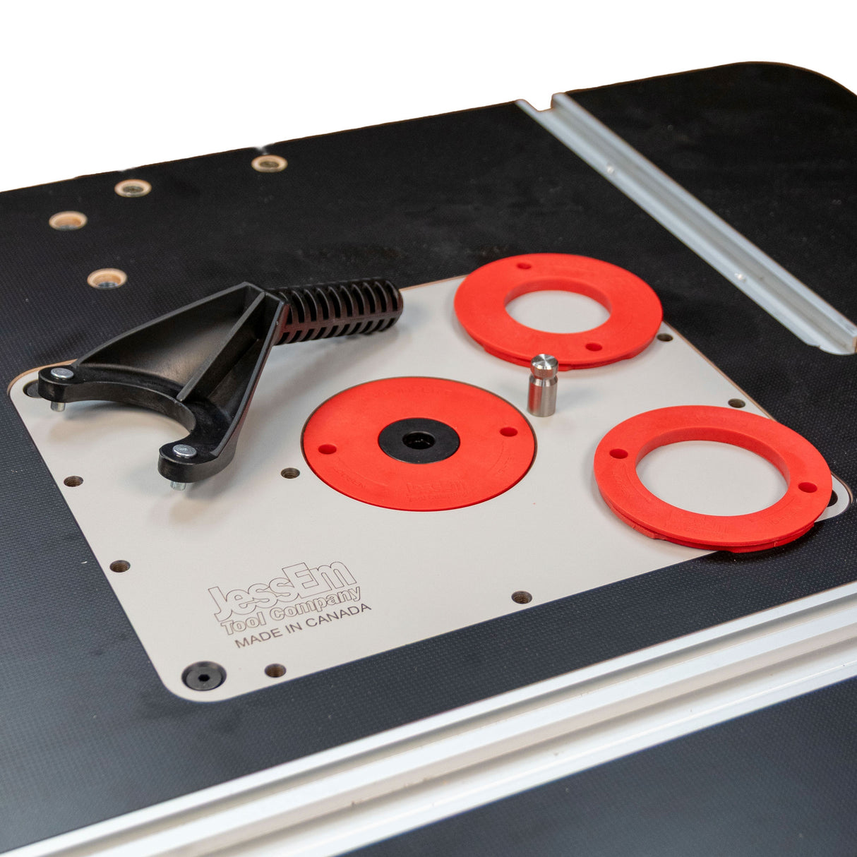 Router table insert plate with red rings and black handle for woodworking