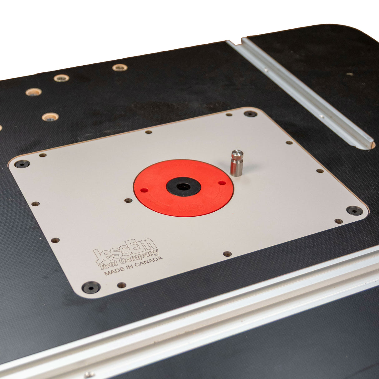 Close-up of woodworking router table insert plate with red ring and miter track